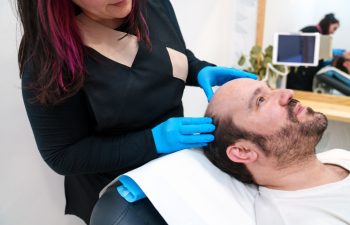 Clinician analyzes patient's scalp before a hair restoration process.