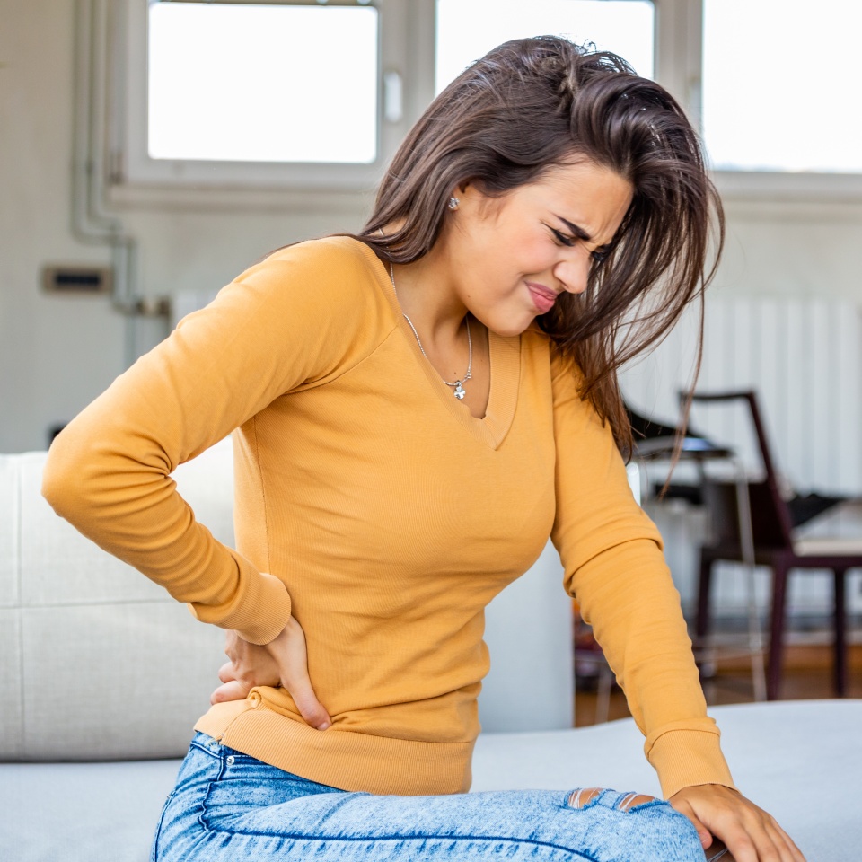 Back Pain. Closeup Of young woman Having Spinal Or Kidney Pain, Backache. Girl Suffering From Painful Feeling, Muscle Or Nerve Pain, Holding Hands On Body. Health Issue Concept.