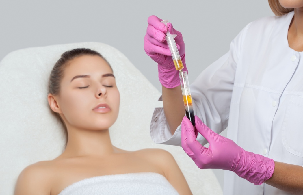 Cosmetologist does prp therapy on the face of a beautiful woman in a beauty salon. There is in vitro blood plasma, ready for injection. Cosmetology concept.