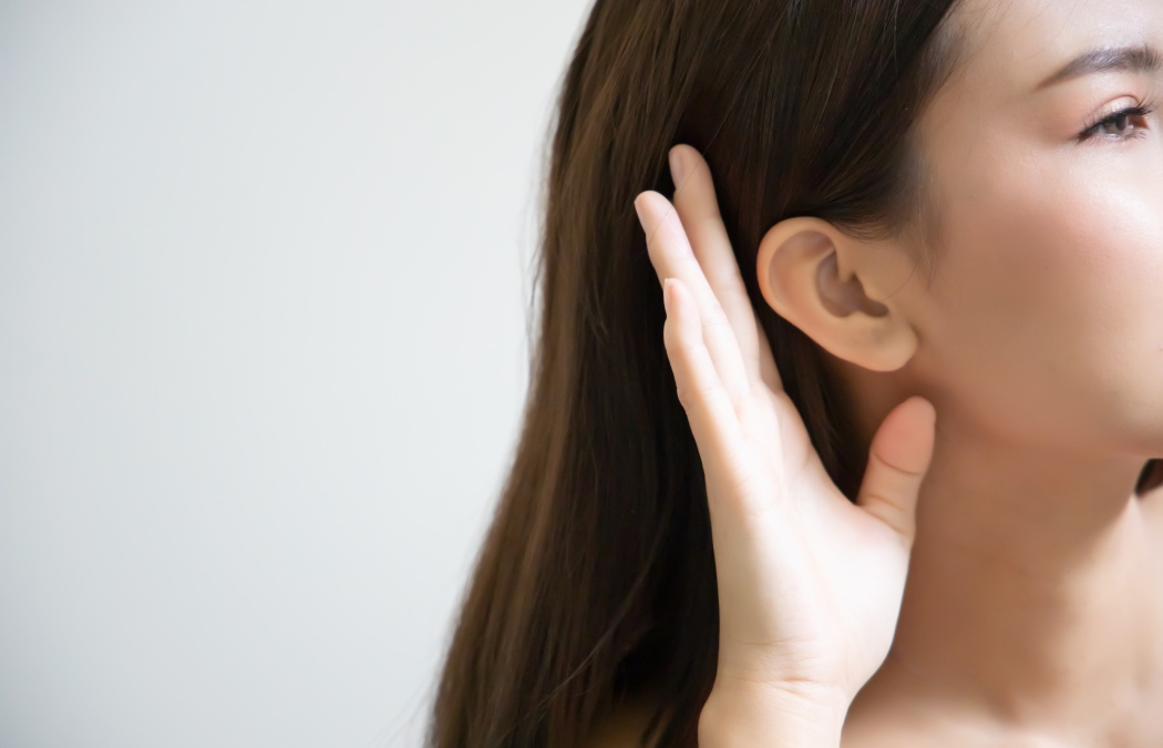 woman listening to something; portrait of southeast asian woman with hearing ear, concept of rumor, gossip, hearing loss, whispering, hard of hearing, fake news, good news, bad news