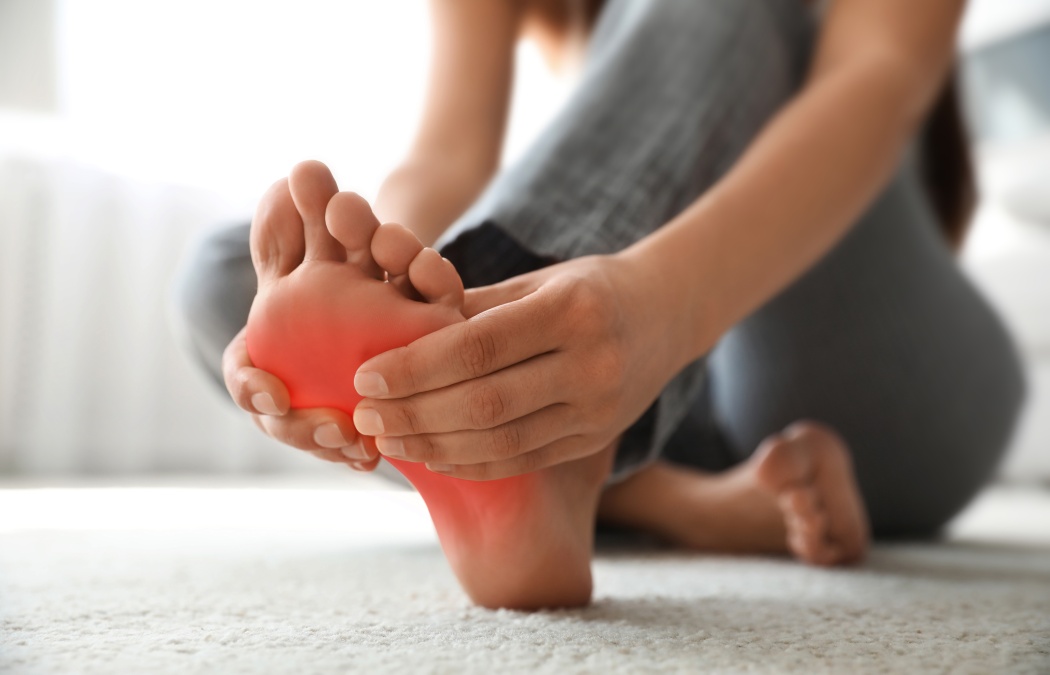 Woman suffering from foot pain at home, closeup
