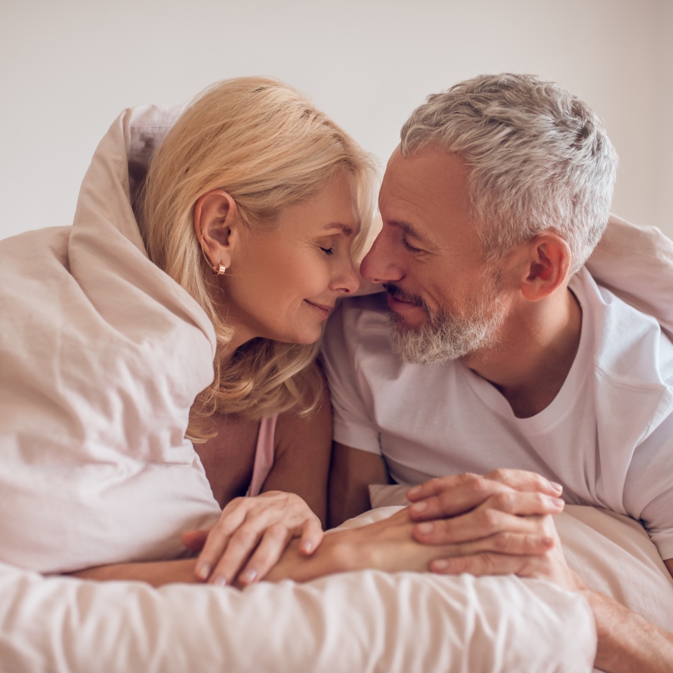 Happy morning. Middle-aged couple having romantic moment in bedroom