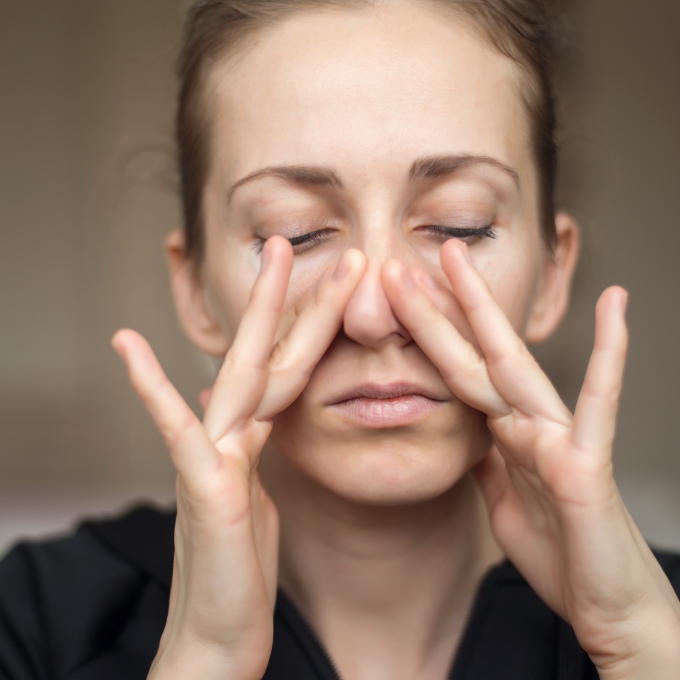 A young woman touches her nose with her fingers because of the loss of her sense of smell, does not feel the smell