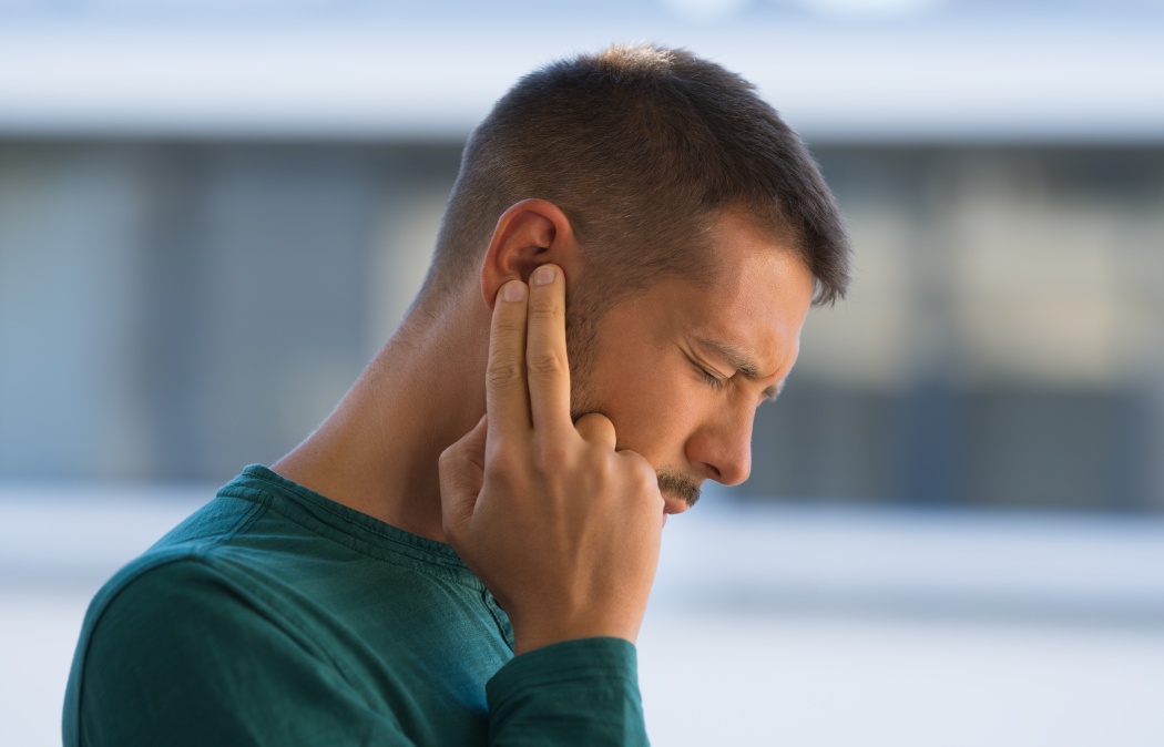 Man with tinnitus. Man touching his ear because of strong earache or ear pain. Otitis