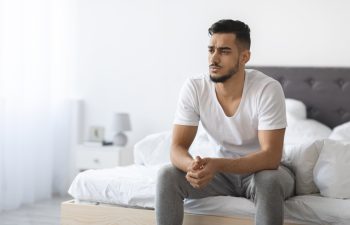 Impotence Concept. Upset Pensive Young Arab Man Sitting On Bed At Home, Anxious Middle Eastern Man Suffering Erectile Dysfunction Resting In Bedroom, Thinking About Health Problems, Copy Space
