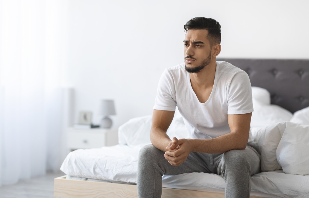 Impotence Concept. Upset Pensive Young Arab Man Sitting On Bed At Home, Anxious Middle Eastern Man Suffering Erectile Dysfunction Resting In Bedroom, Thinking About Health Problems, Copy Space