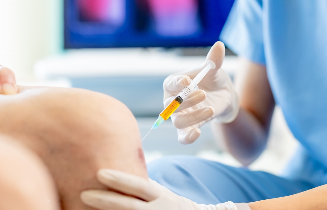 close up of asian female doctor make injection to male elderly senior patient in knee at hospital