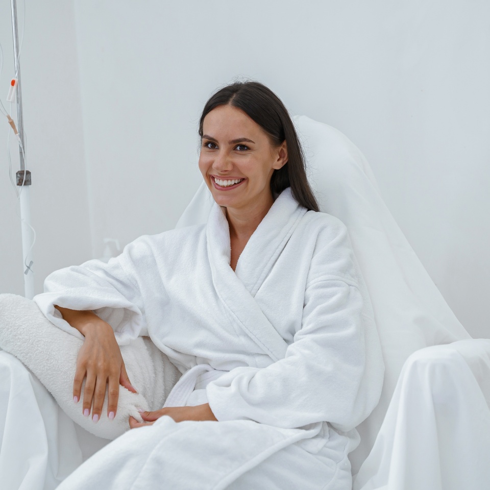 Beautiful woman in white bathrobe during medical procedure in beauty clinic