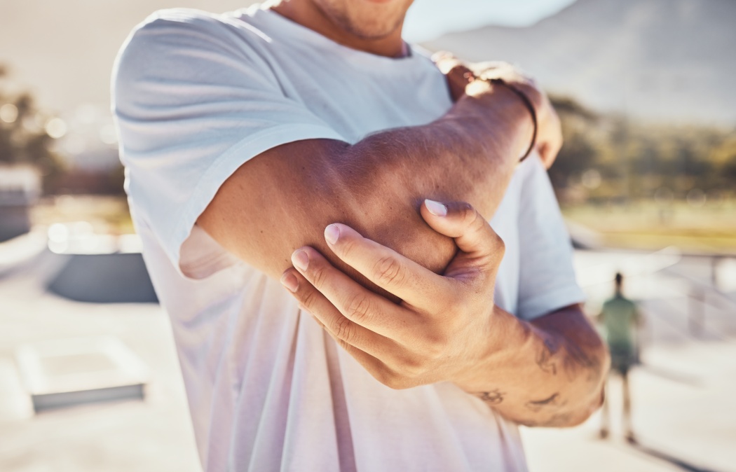 Elbow, joint pain and man, outdoor accident and urban park, emergency and first aid, risk and body problem. Broken arm, bone health and guy in pain, physical therapy injury and muscle inflammation