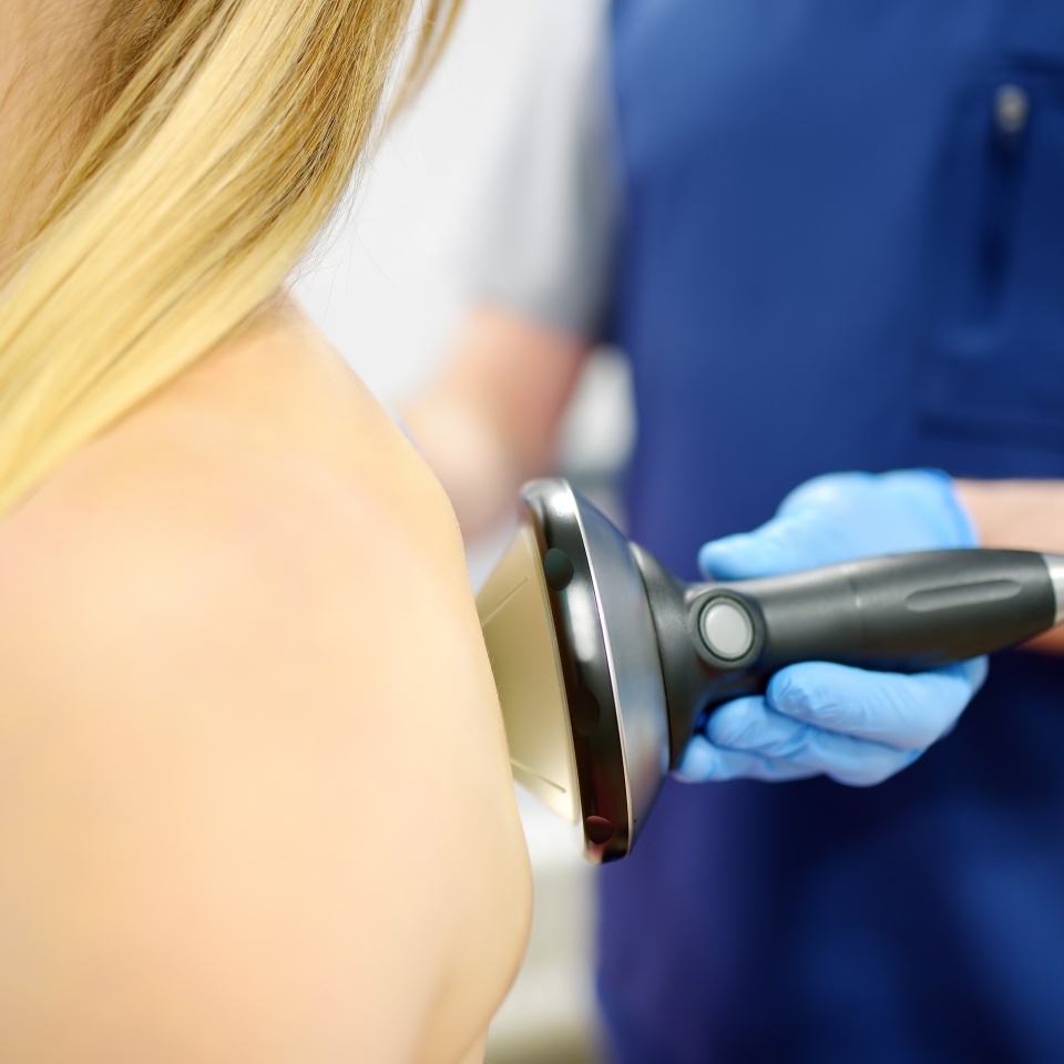 Close up of extracorporeal shockwave therapy in beauty salon. Physical therapy for neck and back muscles with shock waves. Rehabilitation after injury. Modern medical technology.