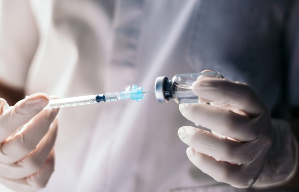 injecting injection vaccine vaccination medicine against covid-19 into a syringe. Close-up