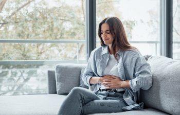 Sick young woman in pain holding belly stomach feeling hurt abdomen ache gastritis pancreatitis symptoms or diarrhea, upset teen girl suffering from indigestion flatulence abdominal problem concept