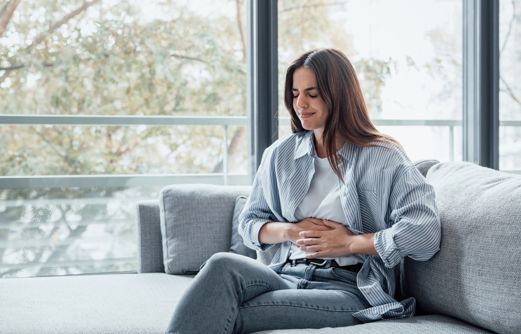 Sick young woman in pain holding belly stomach feeling hurt abdomen ache gastritis pancreatitis symptoms or diarrhea, upset teen girl suffering from indigestion flatulence abdominal problem concept