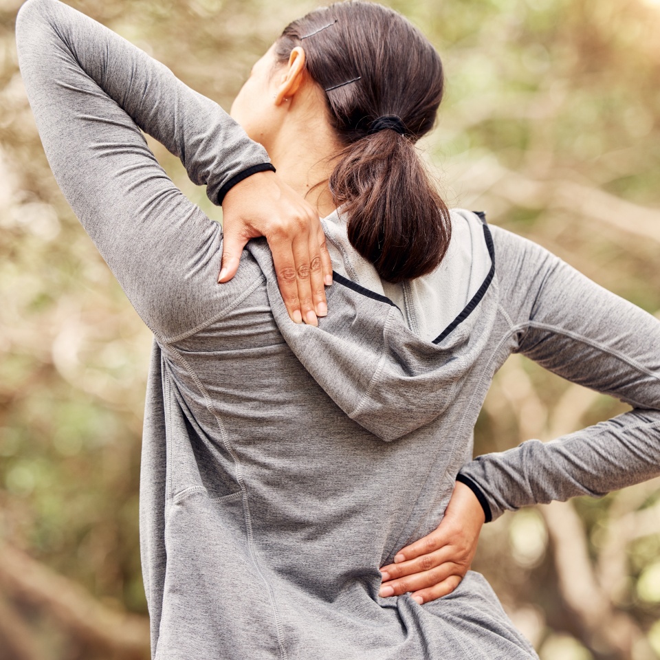 Hands, back pain and runner in nature, person or injury in training for fitness, health and workout in park. Athlete, joint or accident with burnout on countryside for exercise, wellness or emergency