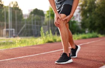 Sportsman with leg injury suffering from knee pain at stadium, closeup. Space for text