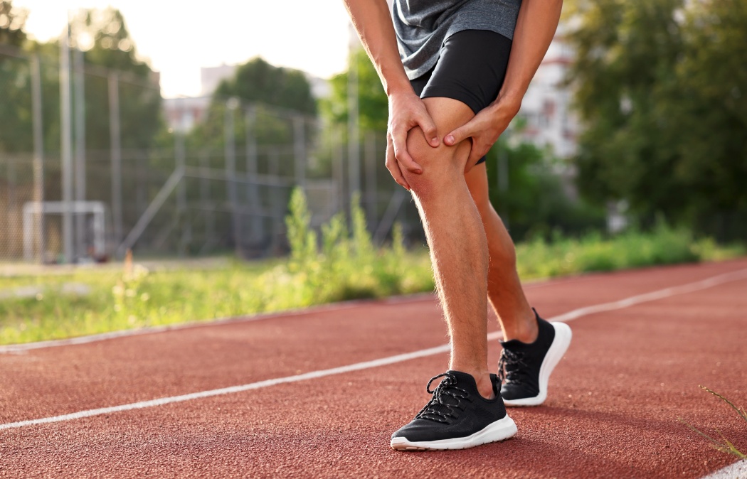 Sportsman with leg injury suffering from knee pain at stadium, closeup. Space for text