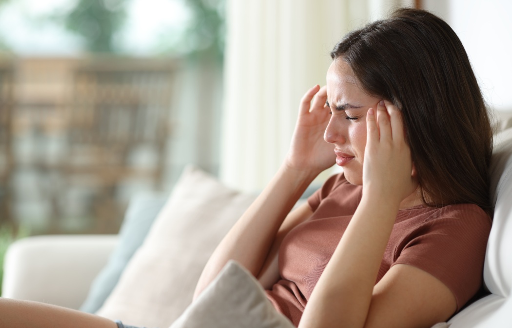 Stressed woman suffering migraine and complaining sitting on a couch at home
