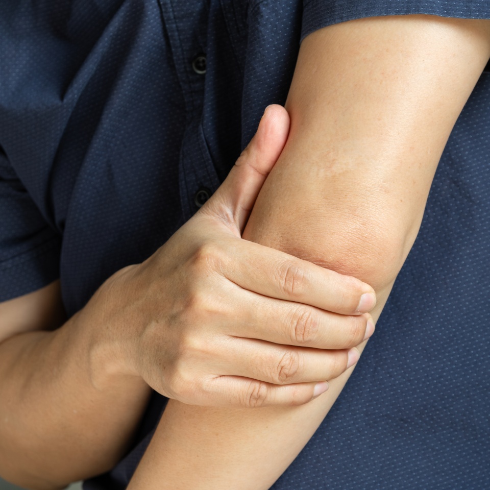 A man has pain in his elbow and tendon muscles and he relieves the pain with a massage. Health and healing concept