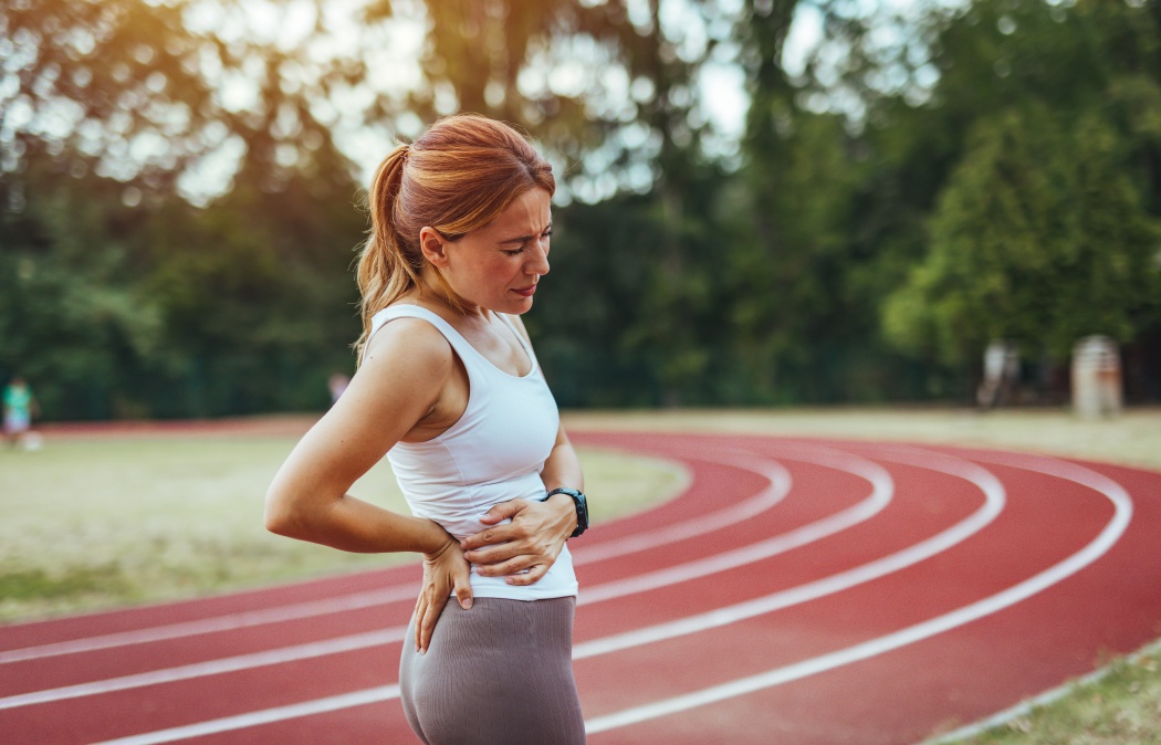 Tired Young Sport girl feel pain on her back and hip while exercising, health care concept. Back pain - woman having painful muscle injury in lower back.