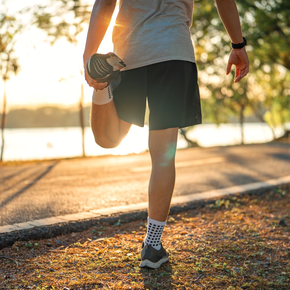 Close up - Man runner stretching leg and feet and preparing for jogging and running in public park outdoors at sunset, Active and healthy lifestyle concept, copy space