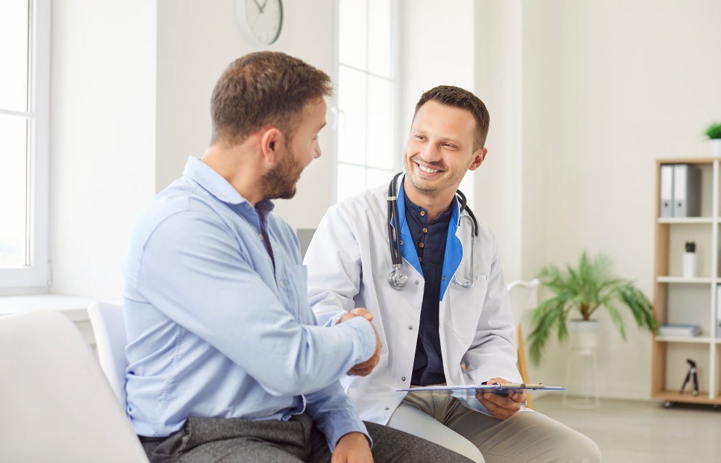 Doctor or nurse shakes hands with a male patient during visit to the hospital clinic. The handshake symbolizes professional medical care, trust, and the importance of patients healthcare.