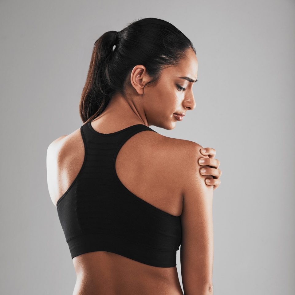 Stress, fitness or girl in studio with shoulder pain, physical strain or massage for tension relief. Woman, sports injury or discomfort on gray background with crisis, accident or mistake in activity