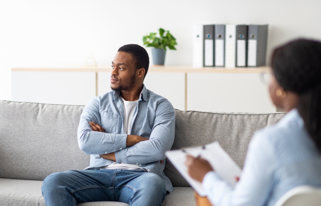 Dealing with client resistance. Professional psychologist working with emotionally detached black male patient at clinic, trying to help him with depression, PTSD, mental problems