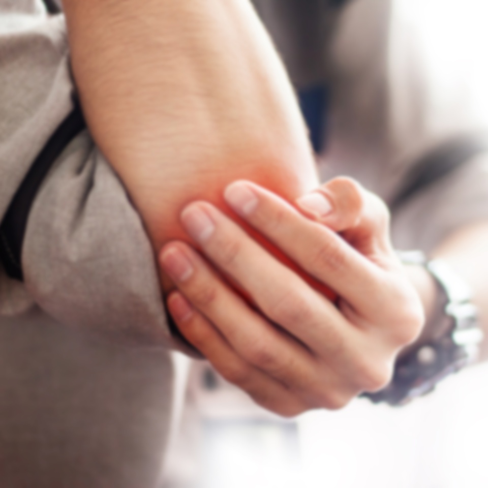 Blurry man holds a painful elbow