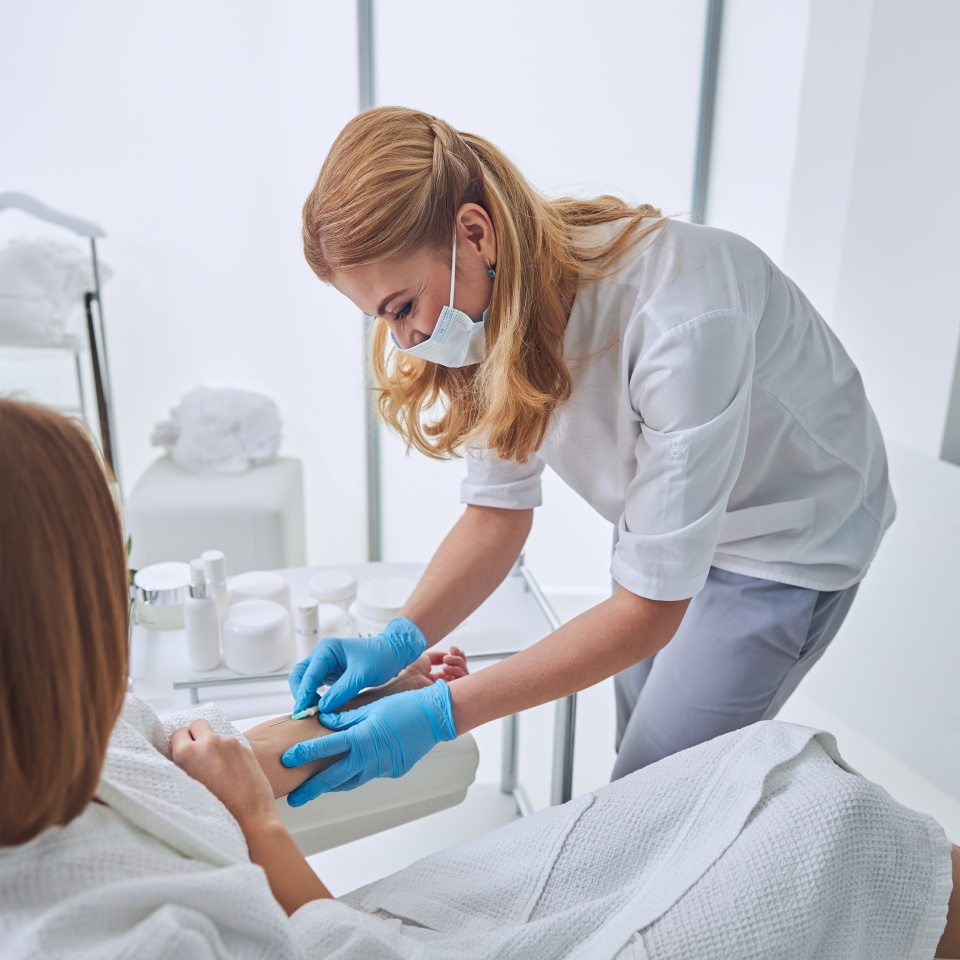 Beautiful elegant physician in white uniform during medical procedure in welness center