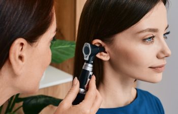 Hearing check-up, otoscopy. Adult woman while ear test with audiologist at medical office. Diagnosis of hear impairment