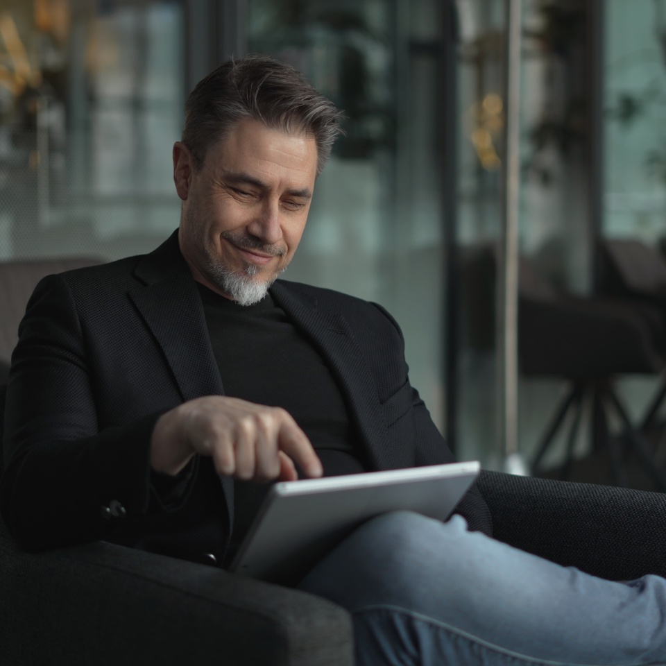 Businessman using tablet computer in office. Happy middle aged man in business casual, Entrepreneur working online, reading finance report, thinking.