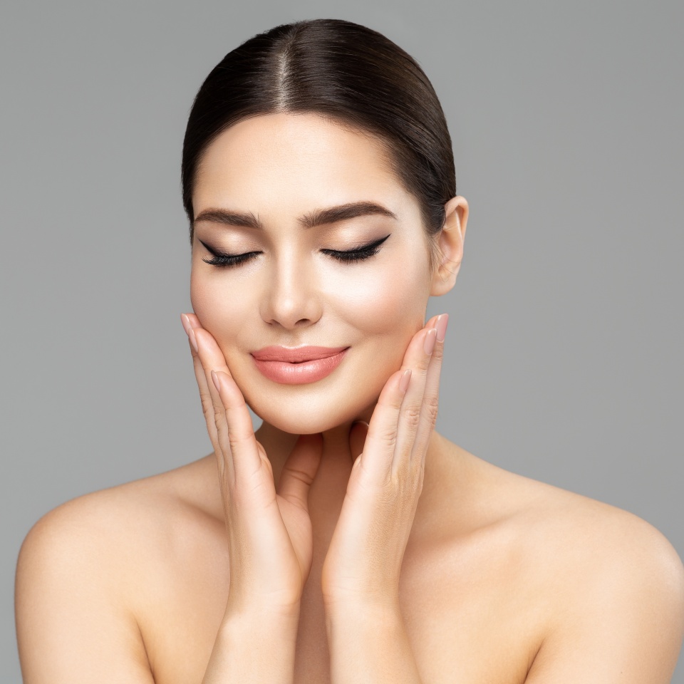 Beauty Face Skin Care. Woman with Full Lips Natural Makeup over isolated background. Beautiful Model enjoying Spa Massage. Facial Plastic Surgery and Dermal Filler Cosmetology