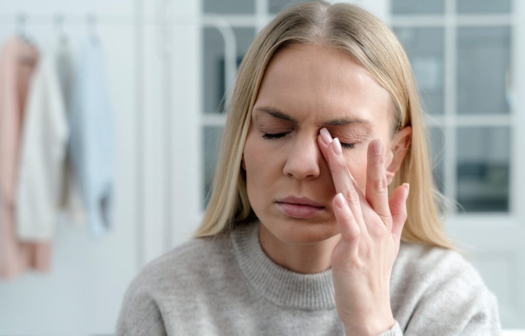 closeup of blonde female feel eye strain or migraine, exhausted young woman worker with headache pain, bad weak blurry vision, eyesight problem