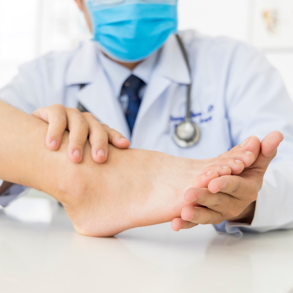 The orthopedic doctor or surgeon in white gown examined the patient with foot pain problem.White clean table or bed with blur background.Hallux or bunion with transfer metatarsalgia.Orthopaedic unit.