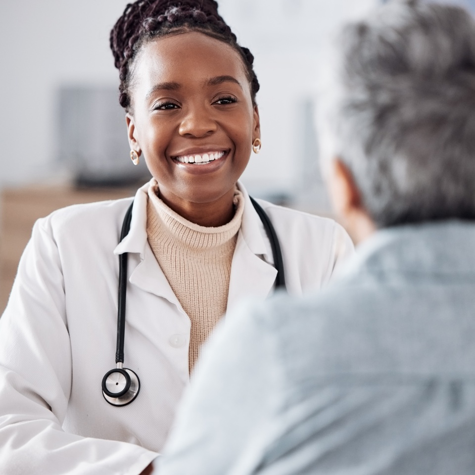 Happy, black woman or doctor consulting a patient in meeting in hospital for healthcare feedback or support. Smile, medical or nurse with a mature person talking or speaking of test results or advice