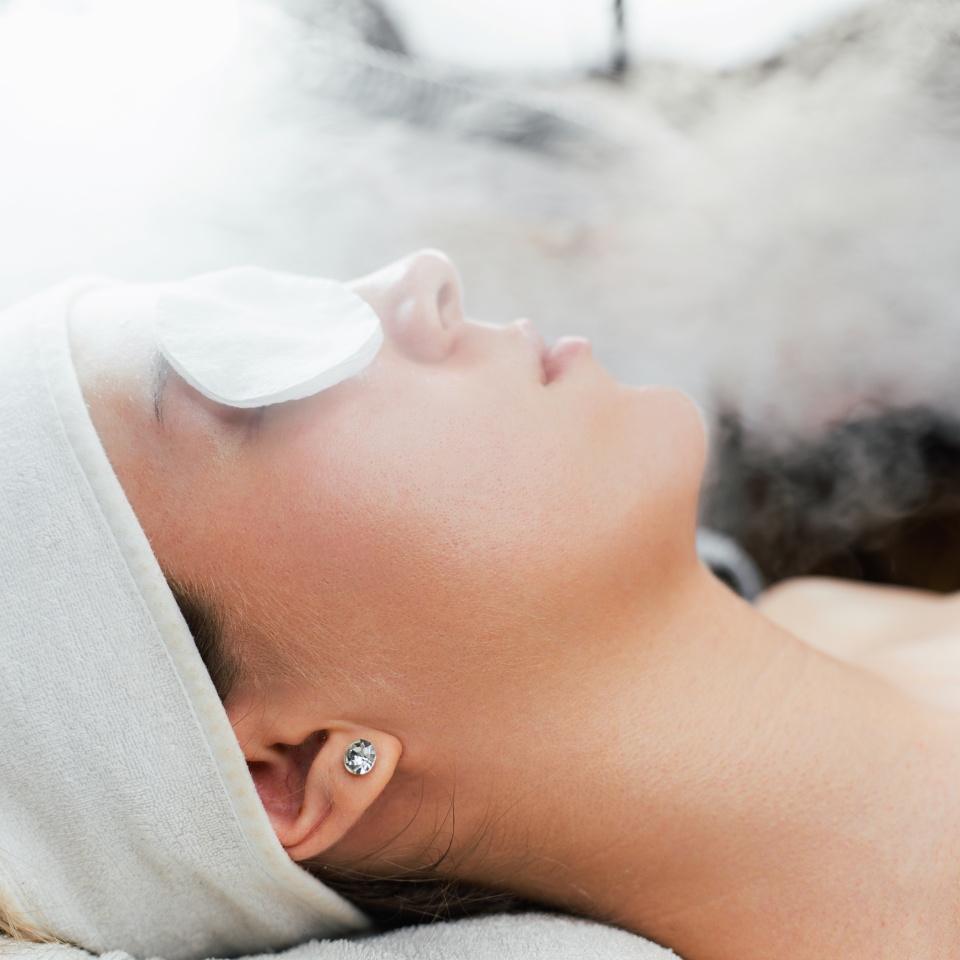 Young woman receiving beauty treatment with thermal ozone facial steamer. Professional cosmetology salon or spa procedure.