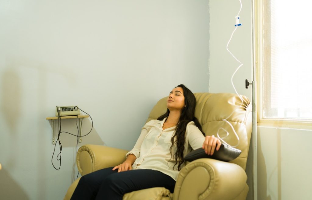 Happy attractive woman relaxing while getting IV drip and vitamin minerals therapy for a better health with a myers cocktail