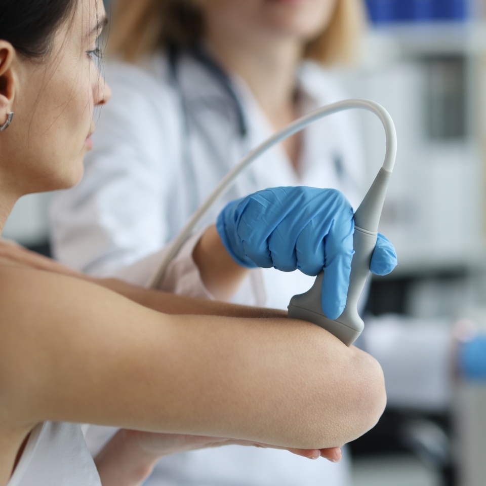 Patient with orthopedic doctor makes ultrasound of elbow joint in clinic. Medical research and arthritis bones concept