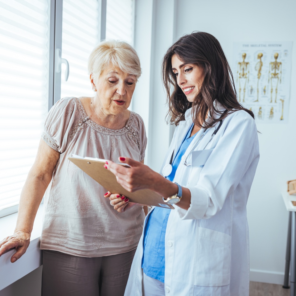 Attractive young female doctor consulting with a patient inside her office at a hospital. Close up of a senior woman having a doctors appointment. A female doctor standing next to female patient