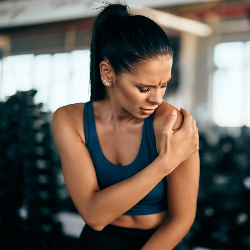 A black-haired gym girl has an injury, feeling a lot of pain in her shoulder.