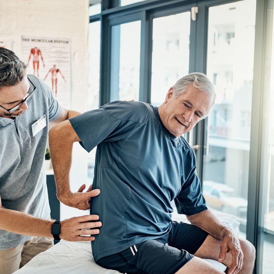 Physio therapist, chiropractor and senior man with back pain for rehabilitation, consulting and exercise. Healthcare, physical therapy and person and patient for medical service, wellness and support