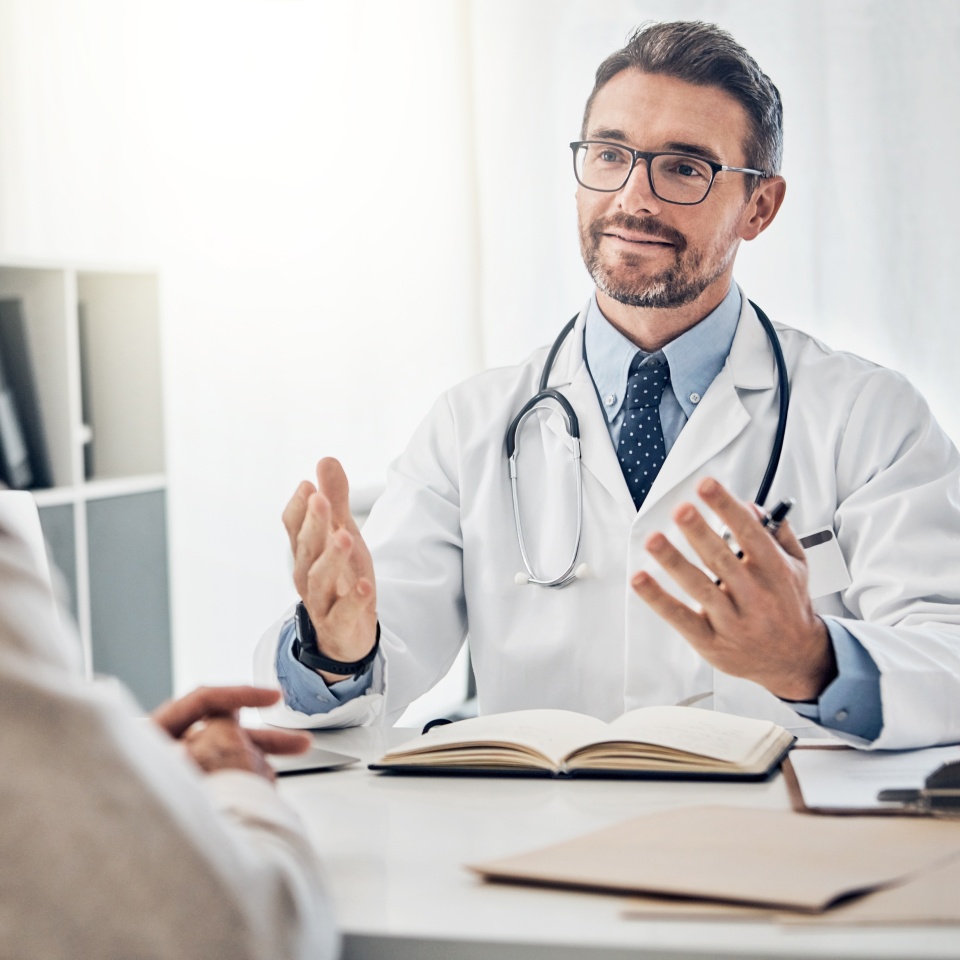 Consultation, man and doctor in office with discussion, help and advice for health insurance. Clinic, senior patient and medical professional at desk with support, trust and healthcare at checkup