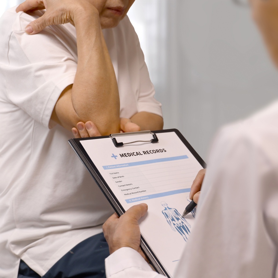 Elderly woman complaining of elbow pain to doctor at orthopedic clinic