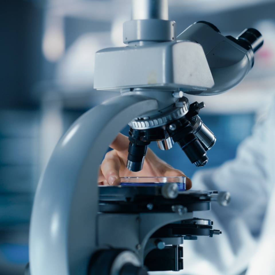 Medical Research and Development Laboratory: Close Up of a Male Scientist Preparing a Biological Sample in a Petri Dish in a Microscope in an Advanced Biotechnology Lab