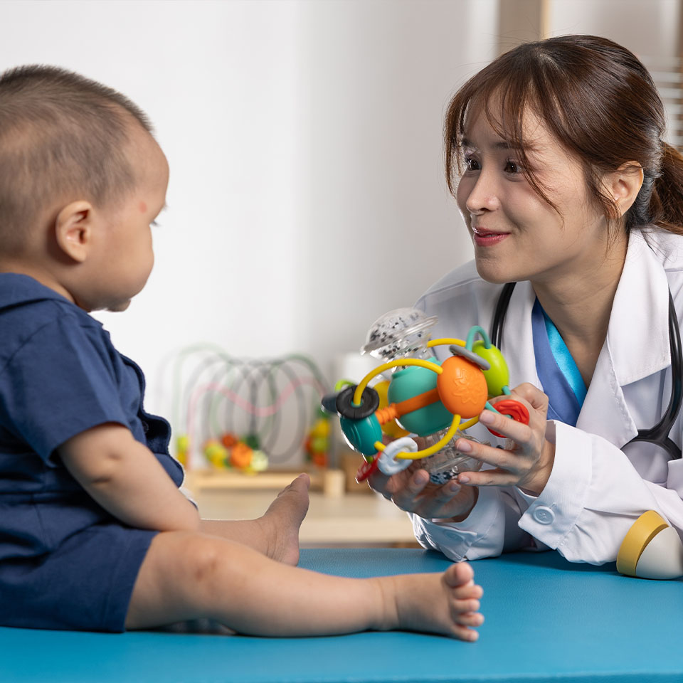 Asian Pediatrician playing with baby using colorful sensory toy