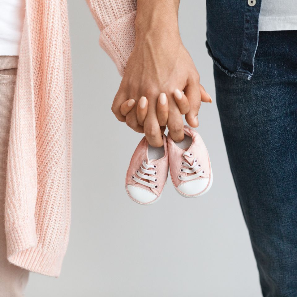 A couple walking by holding hands and baby's boots