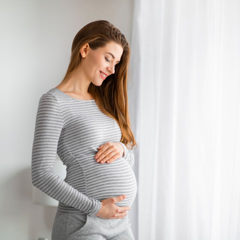 A happy pregnant woma touching gently her belly